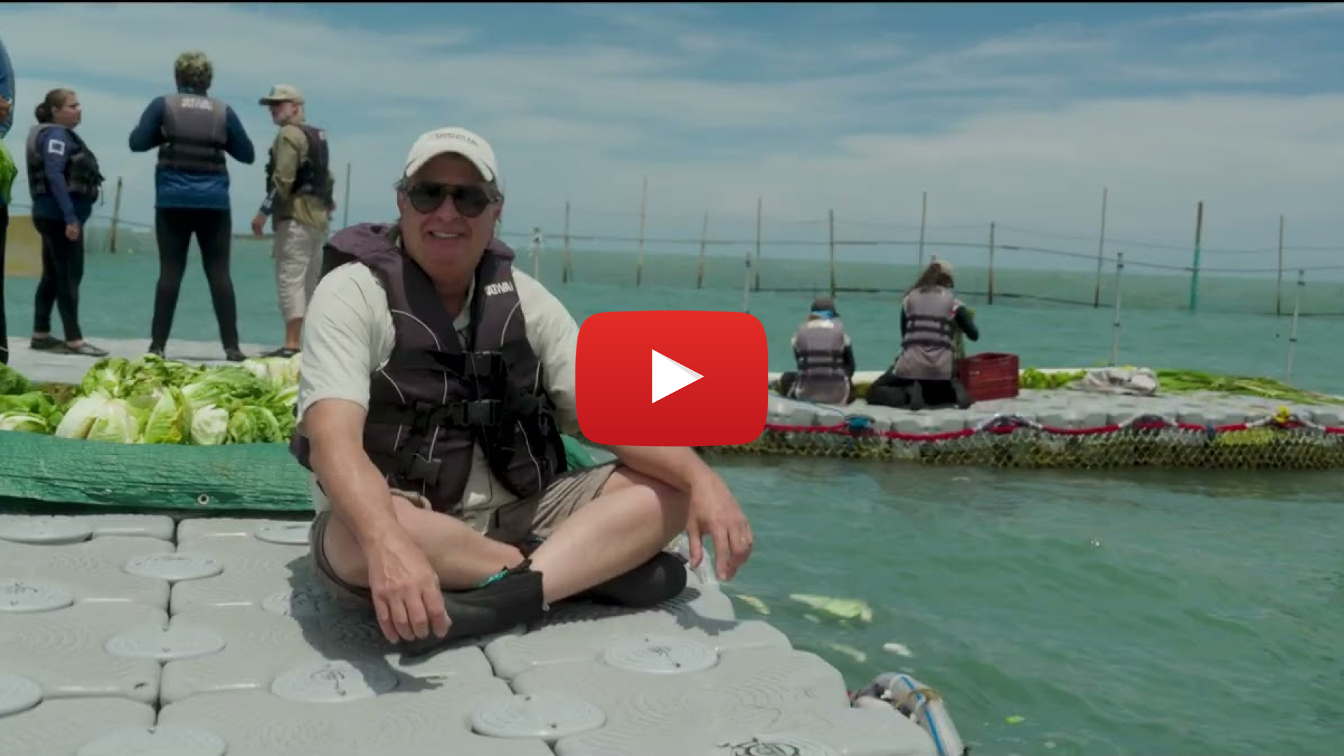 A man sitting on a boat dock. Overlaid is a video play button.