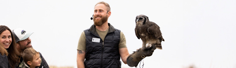 Curtis Evans presenting to ambassador Verreaux's Eagle-owl Oliver to a smiling family.