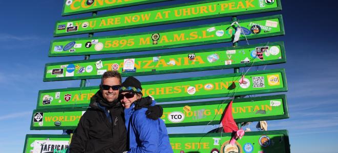 Peregrine Fund NYC Marathon team members Jay and Natalie Kaddas standing in front of an Uhuru Mountain sign