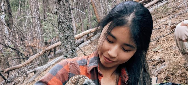 A woman holding an owl in the forest