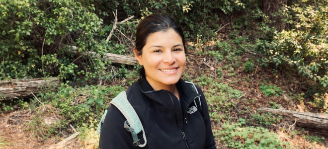 Priscilla Tracy posing and smiling in a forested area.