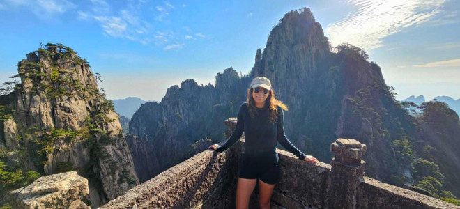 Sara-lee Tucson on an observation deck surrounded by tall mountains and cliffs.