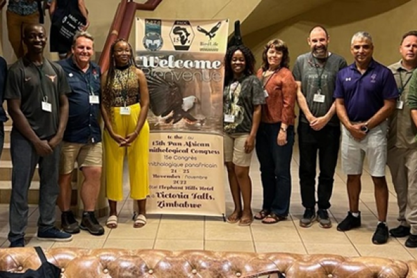 A group of people gathered around a banner for the Pan-African Ornithological Congress
