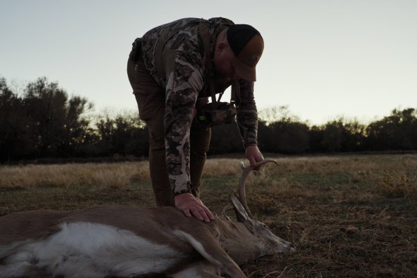 A hunter standing over the body of a deer