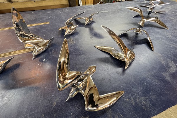 The stainless steel shorebird sculptures from the Inspiration Wall sitting on a table.