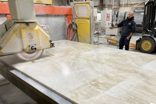 A worker using a diamond saw to cut large slabs of quartzite to size.