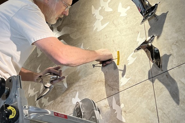 Ross Matteson installing hardware for affixing one of the Inspiration Wall's metal shorebird sculptures to the wall.
