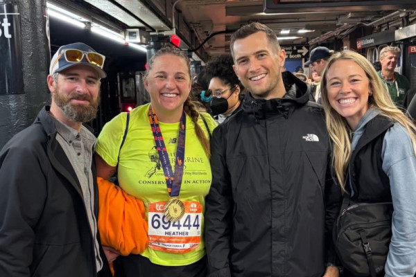 Heather Druffel, a member of TPF's 2025 TCS NYC Marathon team, poses with friends and family wearing her finisher's medal.