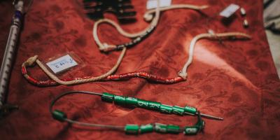 Banding tools and strings of red, green, and black bird bands lying on a red blanket