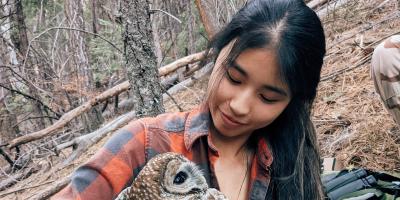 A woman holding an owl in the forest