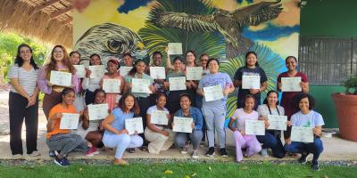 A group of women smile for a photo holding certificates