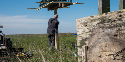 Old wooden nesting structure lays on the ground with new aluminum structure in background