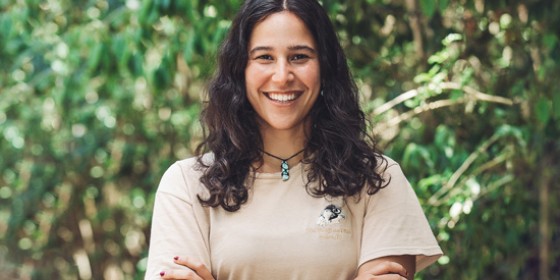 A biologist smiling with her arms crossed in front of dense foilage