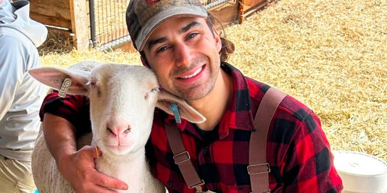 Michael R. posing and smiling while hugging a sheep.