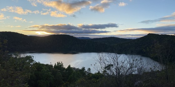 A sunset-lit lake in front of a partly cloudy sky.