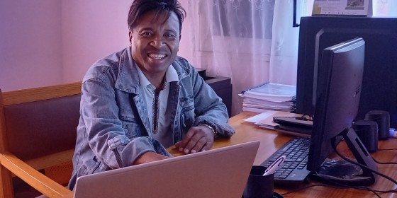 Andrianarjaona Razafy sitting at a desk and smiling.