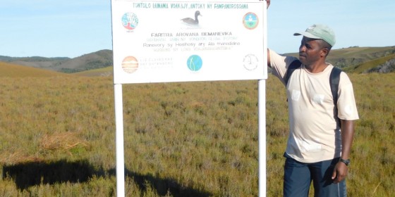 Donatien Randrianjafiniasa leaning against a sign for Bemanevika Protected Area.