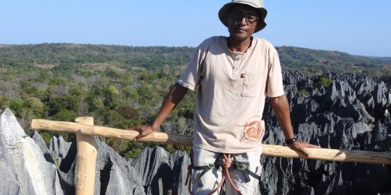 Gilbert Razafimanjato Mandrozo posing on an observation deck above a cliff.