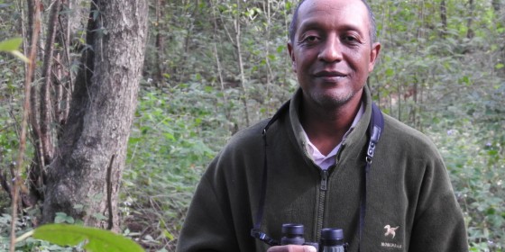 Juliot Ramamonjisoa posing in a forest while holding binoculars.