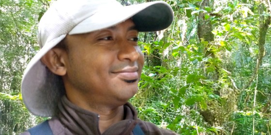 A closeup of Yverlin Pruvot in the forest smiling at something in the distance