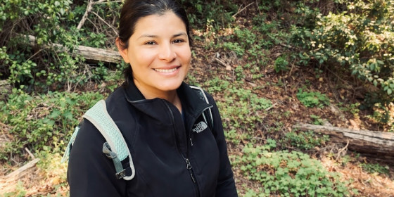 Priscilla Tracy posing and smiling in a forested area.