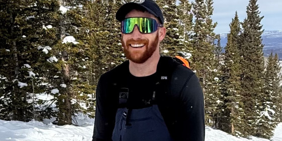 Sam Ditesheim posing for a photo on a snow-covered slope with distant mountains in the background.
